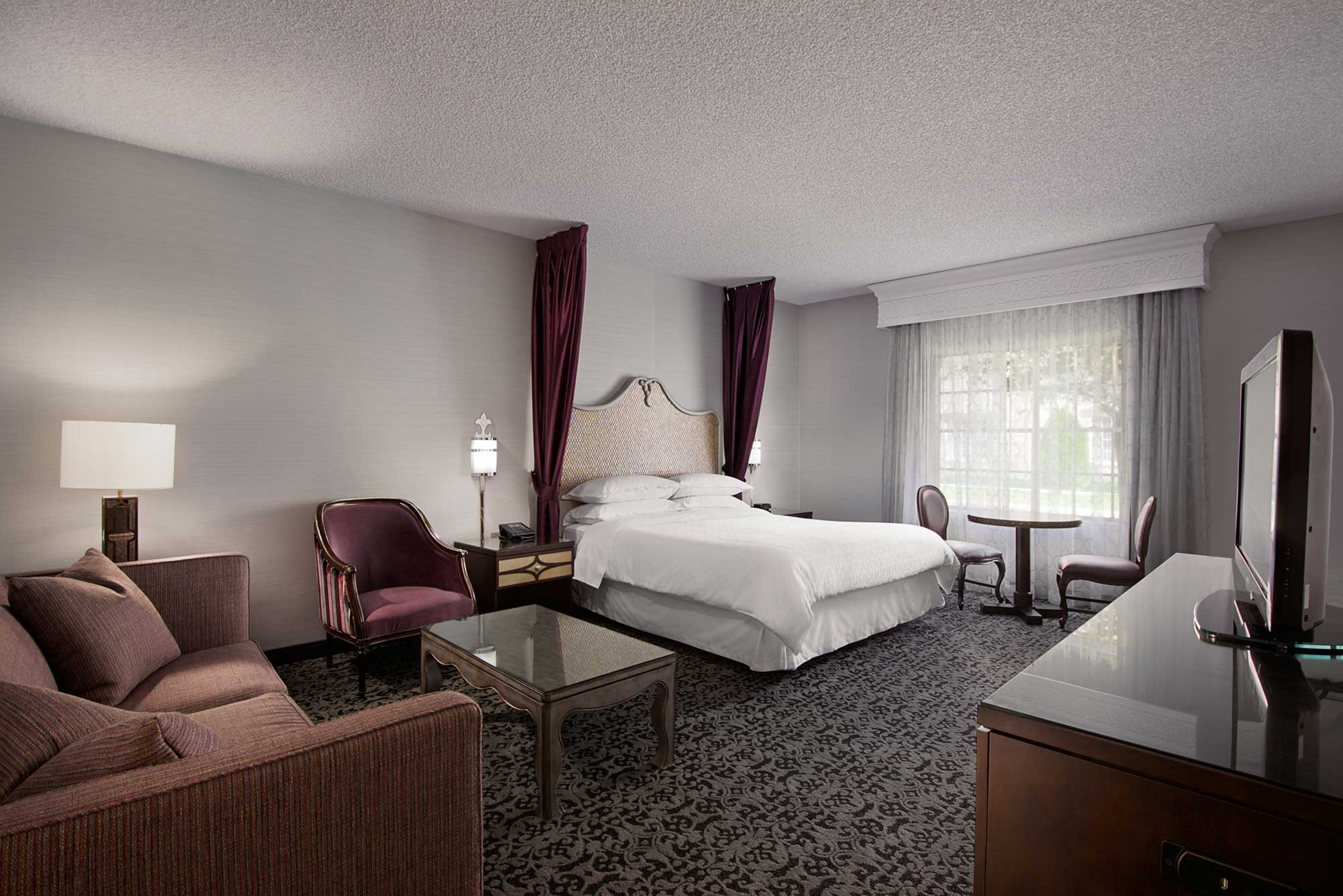Castle-themed hotel room with a queen bed, plum accents, and royal décor at Anaheim Majestic Garden Hotel near Disneyland® Resort
